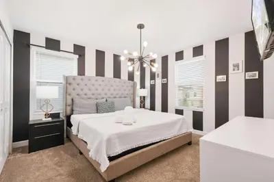 a bedroom with a large bed with striped walls at Storey Lake Getaway Pool SPA Theater in Kissimmee