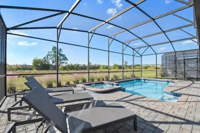 a glass house with a swimming pool and a patio at Resort Home: Game Room, Pool, Near Disney in Kissimmee