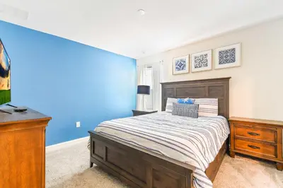 a bedroom with a bed and a blue wall at Resort Home: Game Room, Pool, Near Disney in Kissimmee
