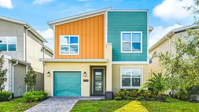 an orange and green house with a blue garage at Storey Lake Cozy Resort Home Pool Spa Disney Theme in Kissimmee
