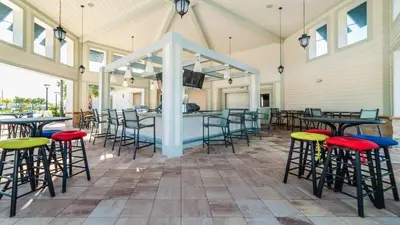 a covered patio with tables and chairs and a bar at Storey Lake Cozy Resort Home Pool Spa Disney Theme in Kissimmee