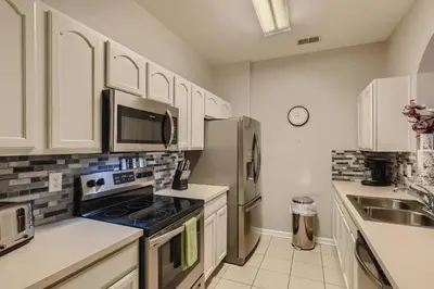 a kitchen with white cabinets and a stainless steel refrigerator at C2821-303 Windsor Hills Resort 3 Bedrm Water Park in Orlando