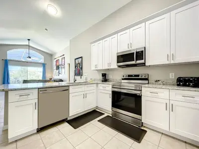 a kitchen with white cabinets and a stove top oven at H2631E Resort Single Level POOL SPA Home Disney in Kissimmee