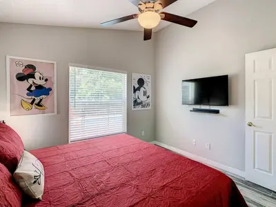 a bedroom with a red bed and a flat screen tv at H2553O Single Level 5 Bedrm Pool 3Miles Disney in Kissimmee