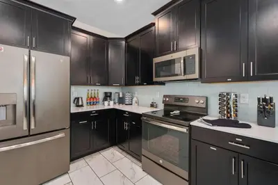 a kitchen with black cabinets and stainless steel appliances at Magic Marvel Getaway in Kissimmee