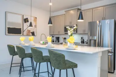 a kitchen with a large white island with green chairs at Charming 4Bd w Private Pool @ Storey Lake Resort 2653 in Kissimmee