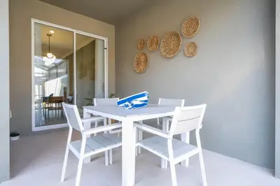 a white table with white chairs and plates on a wall at Charming 4Bd w Private Pool @ Storey Lake Resort 2653 in Kissimmee