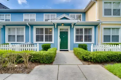 a blue house with a green door and a white fence at Haven Beautiful 3 BR TH in Gated Resort Community in Kissimmee