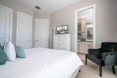 a bedroom with a white bed and a black chair at Awesome 4 Suites Villa 5 Min to Disney in Orlando