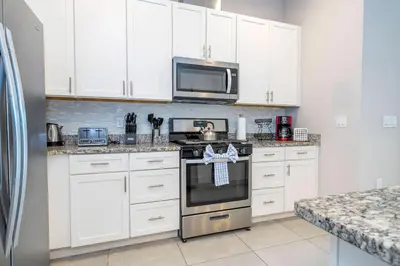 a kitchen with white cabinets and a stove top oven at Awesome 4 Suites Villa 5 Min to Disney in Orlando