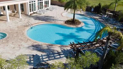 a swimming pool with chairs and a palm tree at Fabulous townhome near the Parks in Kissimmee