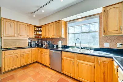 a kitchen with wooden cabinets and a sink and a window at 1-Acre Backyard and Gym Spacious Apopka Escape! in Orlando