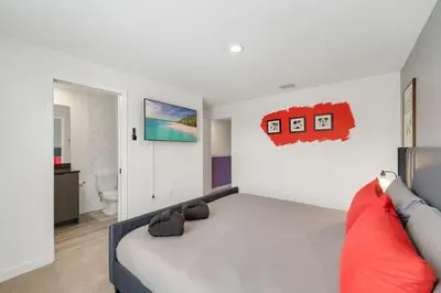 a bedroom with a large bed with red pillows at 3MI from Disney- Modern 3BD 3BA + Grill in Kissimmee