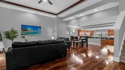 a living room with a black couch and a kitchen at Sun, Fun & Summer Getaway - TownHome by Disney! in Orlando