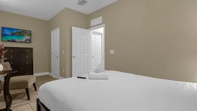 a bedroom with a large white bed and a desk at Sun, Fun & Summer Getaway - TownHome by Disney! in Orlando