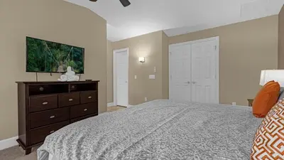 a bedroom with a bed and a flat screen tv at Sun, Fun & Summer Getaway - TownHome by Disney! in Orlando