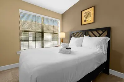 a bedroom with a white bed with a teddy bear on it at Cozy & Elegant 4BR Enchanted Townhouse - 1 Mile to Disney with Resort Pool, Gym, & Jacuzzi in Orlando