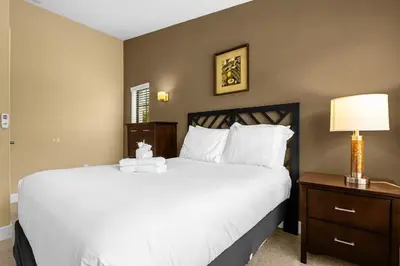 a bedroom with a large white bed and a nightstand at Cozy & Elegant 4BR Enchanted Townhouse - 1 Mile to Disney with Resort Pool, Gym, & Jacuzzi in Orlando
