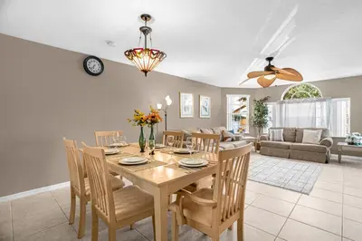 a dining room and living room with a table and chairs at Ground Level Condo with Garden Patio in Kissimmee