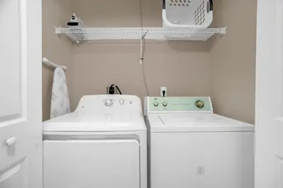 a small white laundry room with a washer and dryer at Ground Level Condo with Garden Patio in Kissimmee