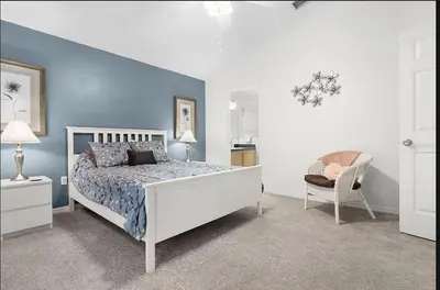 a bedroom with a white bed and a chair at Tropical Escape by Shine Villas 244 villa in Kissimmee