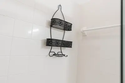 a white tiled bathroom with two black baskets on the wall at Cozy 4Bedrooms At Lucaya- 7 miles from Disney in Kissimmee