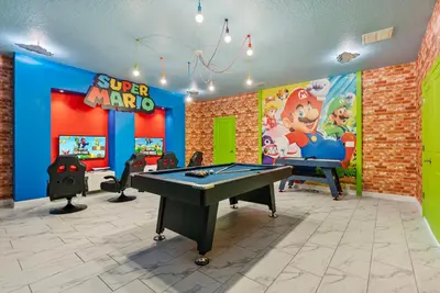 a game room with a ping pong table and a video game at New Home 9 Bedrooms and 5 Bath At Storey Lake in Kissimmee