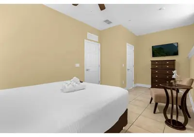 a bedroom with a bed and a table and a dresser at Your Summer Getaway Awaits - Townhome by Disney! in Orlando