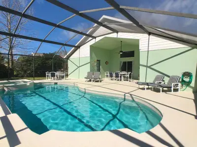 a swimming pool with chairs and a patio with a building at The Oasis in Orlando