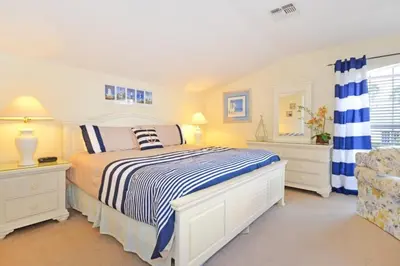 a white bedroom with a bed and a chair at Lake House at Formosa home in Orlando