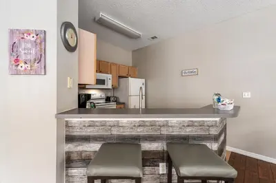a kitchen with two stools at a counter in a room at Near Disney + FREE Clubhouse + Pool + GYM + Sauna in Kissimmee