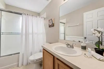 a bathroom with a sink and a toilet and a mirror at Near Disney + FREE Clubhouse + Pool + GYM + Sauna in Kissimmee