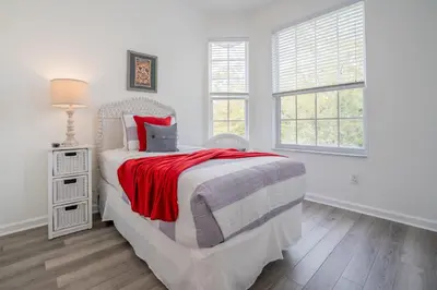 a white bedroom with a bed and two windows at Windsor Palms Gem: Stylish and Fully Equipped in Kissimmee