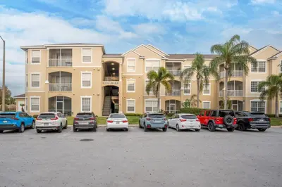 a large apartment building with cars parked in a parking lot at Windsor Palms Gem: Stylish and Fully Equipped in Kissimmee