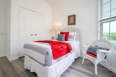 a white bedroom with a bed and a chair at Windsor Palms Gem: Stylish and Fully Equipped in Kissimmee