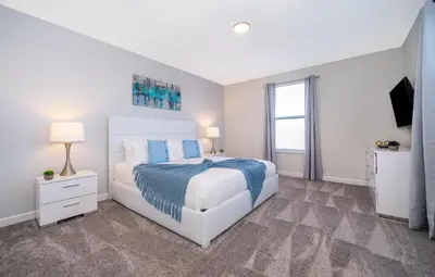 a white bedroom with a large bed and a window at 800MO VILLA 5 BED/5 BA in Orlando