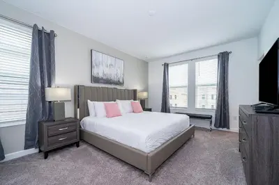 a bedroom with a bed and a tv and windows at 4176SS STOREY LAKE VILLA WITH PRIVATE POOL in Kissimmee