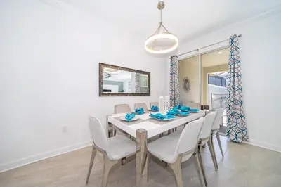 a dining room with a white table and chairs at 4188FA TOWNHOUSE 4 BEDROOMS & 3 BATHROOMS + POOL in Kissimmee