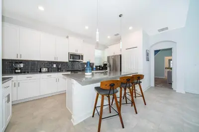 a kitchen with white cabinets and bar stools at 4338JC VILLA 5 BED/5 BA (SANITIZED) in Kissimmee