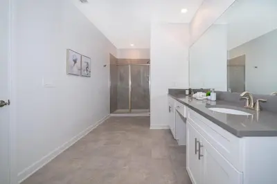 a white bathroom with two sinks and a shower at 4338JC VILLA 5 BED/5 BA (SANITIZED) in Kissimmee
