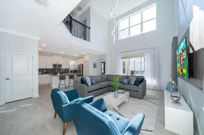 a living room with two blue chairs and a tv at 4338JC VILLA 5 BED/5 BA (SANITIZED) in Kissimmee