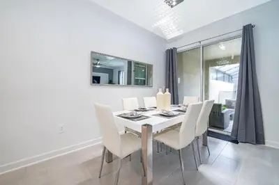 a dining room with a white table and white chairs at 2472PB TOWNHOUSE 4 BEDROOMS & 3 BATHROOMS + POOL in Kissimmee