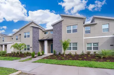 a large apartment building with a driveway at 2472PB TOWNHOUSE 4 BEDROOMS & 3 BATHROOMS + POOL in Kissimmee