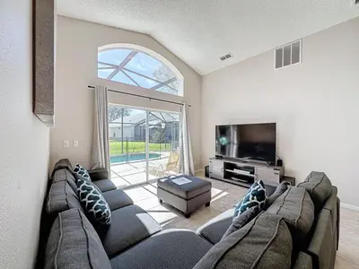 a living room with a large couch and a tv at 5 Star Home Private Pool & JaccuzziFree Wi-Fi villa in Kissimmee