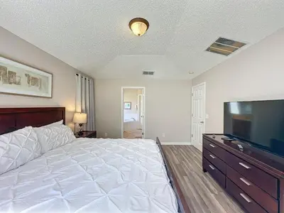 a bedroom with a large bed and a flat screen tv at 5 Star Home Private Pool & JaccuzziFree Wi-Fi villa in Kissimmee
