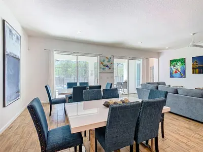 a dining room and living room with a table and chairs at Elegant Villa 12BD-12BA Vacation Haven BV368 in Kissimmee