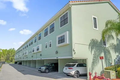 a building with two cars parked in a parking lot at Summer Deal - Relax & Unwind, Townhome by Disney! in Orlando