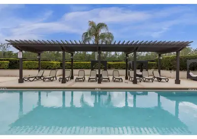 a pergola and chairs next to a swimming pool at Sunny Summer Awaits - Renovated Townhome by Disney! in Orlando