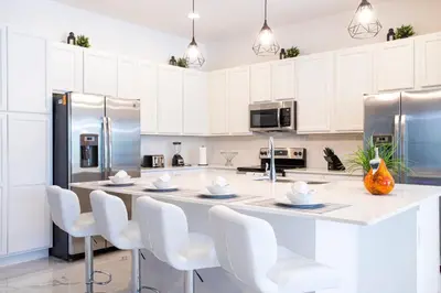 a kitchen with white cabinets and a large island with white chairs at Gorgeous Family Home! Sleeps 28 BLV103 in Kissimmee
