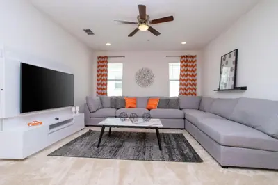 a living room with a gray couch and a flat screen tv at Gorgeous Family Home! Sleeps 28 BLV103 in Kissimmee